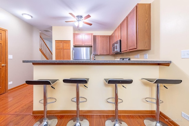 kitchen featuring a kitchen breakfast bar, stainless steel refrigerator, and ceiling fan