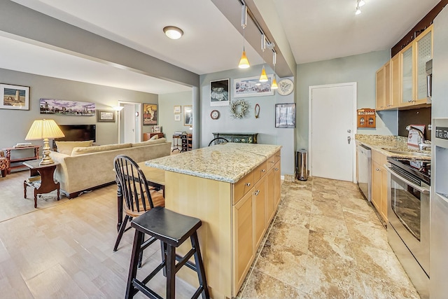 kitchen featuring light stone countertops, appliances with stainless steel finishes, sink, a center island, and a breakfast bar area