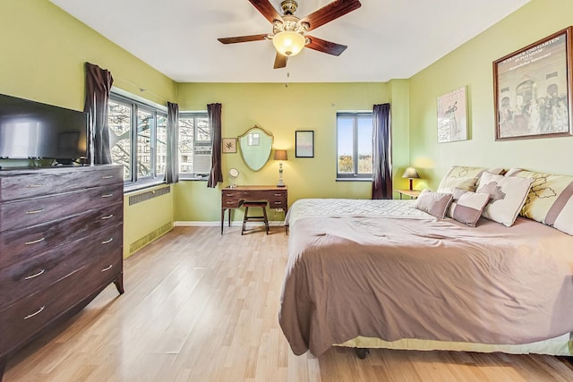 bedroom with ceiling fan, light hardwood / wood-style floors, and radiator heating unit