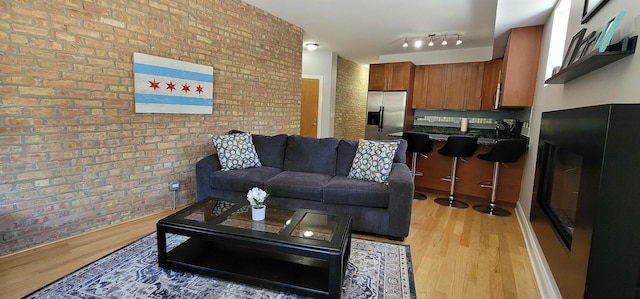 living room with light wood-type flooring and brick wall