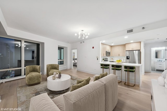 living room with sink, light hardwood / wood-style floors, and a notable chandelier