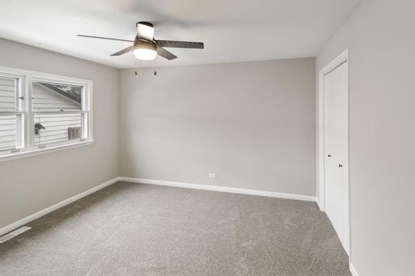 unfurnished room with dark carpet and ceiling fan