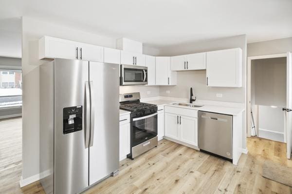 kitchen featuring appliances with stainless steel finishes, light hardwood / wood-style floors, white cabinetry, and sink