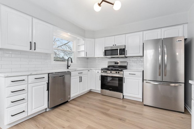 kitchen featuring white cabinets, decorative backsplash, light hardwood / wood-style floors, and appliances with stainless steel finishes