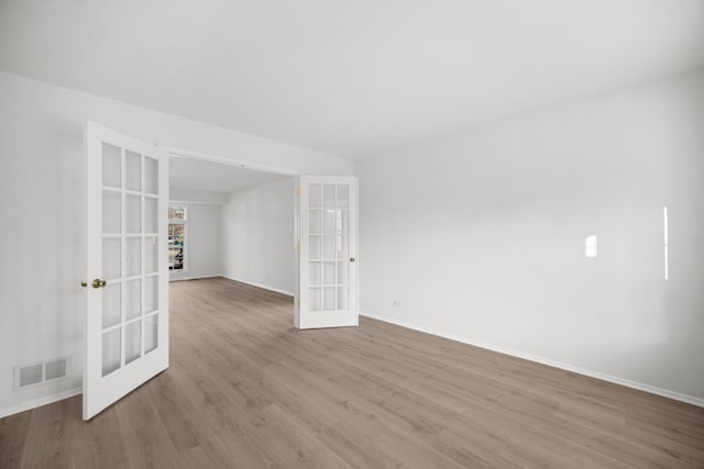 empty room with light hardwood / wood-style floors and french doors