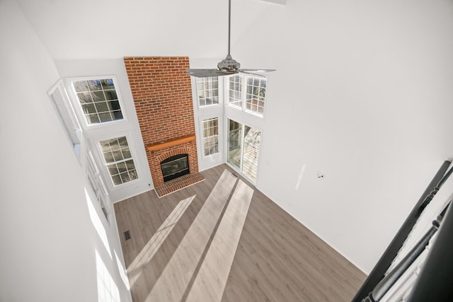 living room featuring a fireplace, a high ceiling, hardwood / wood-style flooring, and ceiling fan