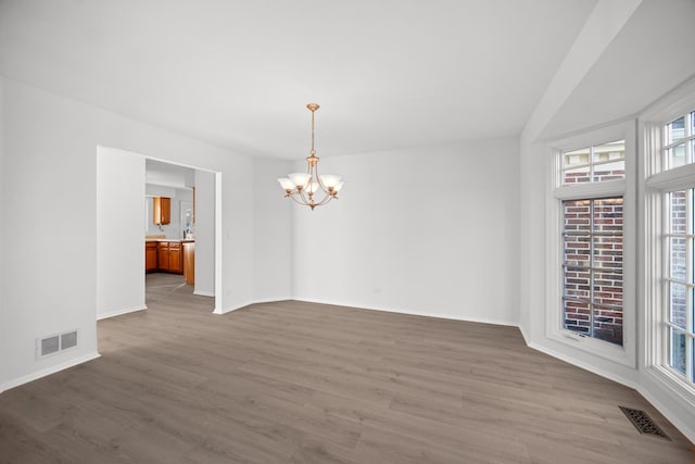 spare room with a chandelier and wood-type flooring