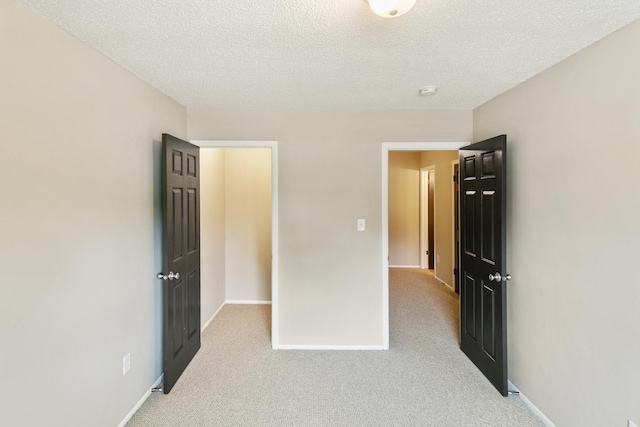 unfurnished bedroom featuring a textured ceiling and light colored carpet