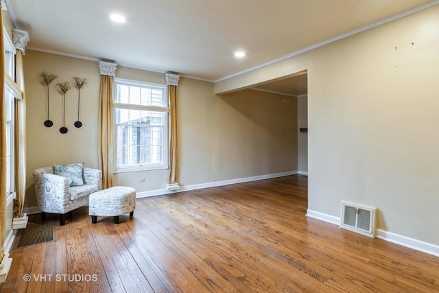 unfurnished room with ornamental molding, visible vents, baseboards, and hardwood / wood-style flooring