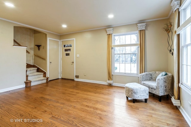 sitting room with baseboards, ornamental molding, stairway, and light wood-style floors