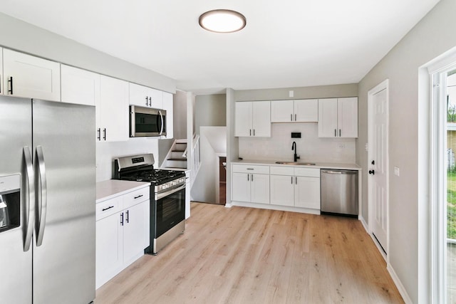 kitchen featuring white cabinetry, sink, stainless steel appliances, and light hardwood / wood-style floors