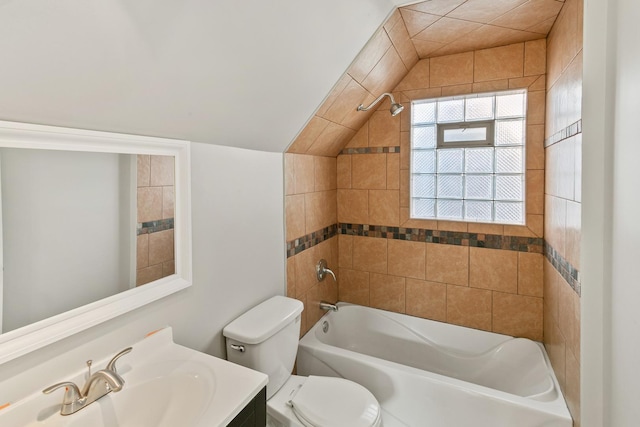 full bathroom featuring toilet, vanity, lofted ceiling, and tiled shower / bath