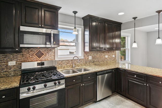 kitchen with a wealth of natural light, sink, decorative light fixtures, and appliances with stainless steel finishes