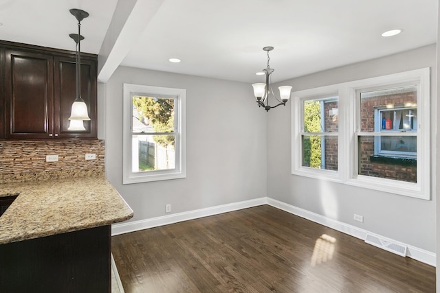 unfurnished dining area featuring dark hardwood / wood-style floors, a wealth of natural light, and a notable chandelier