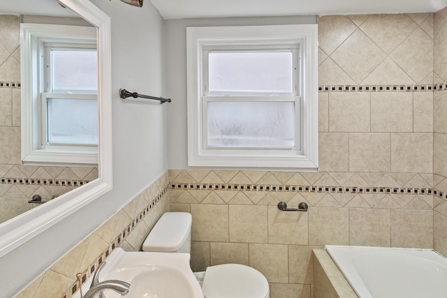 bathroom featuring a tub, a wealth of natural light, tile walls, and toilet