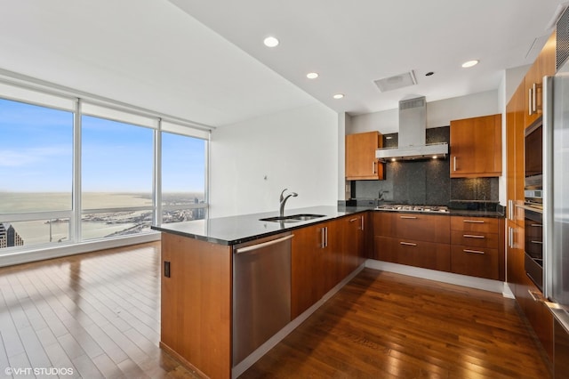 kitchen with expansive windows, a water view, sink, wall chimney exhaust hood, and stainless steel appliances