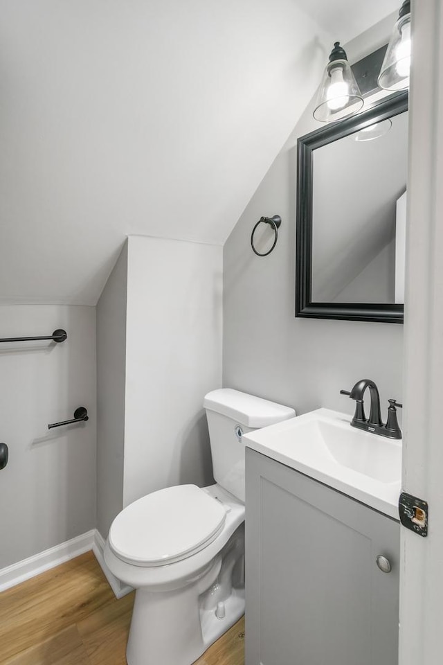 bathroom featuring hardwood / wood-style floors, toilet, vanity, and vaulted ceiling