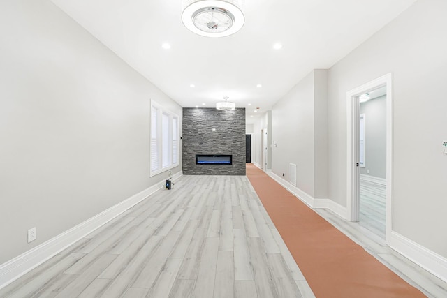 unfurnished living room with light hardwood / wood-style flooring and a stone fireplace