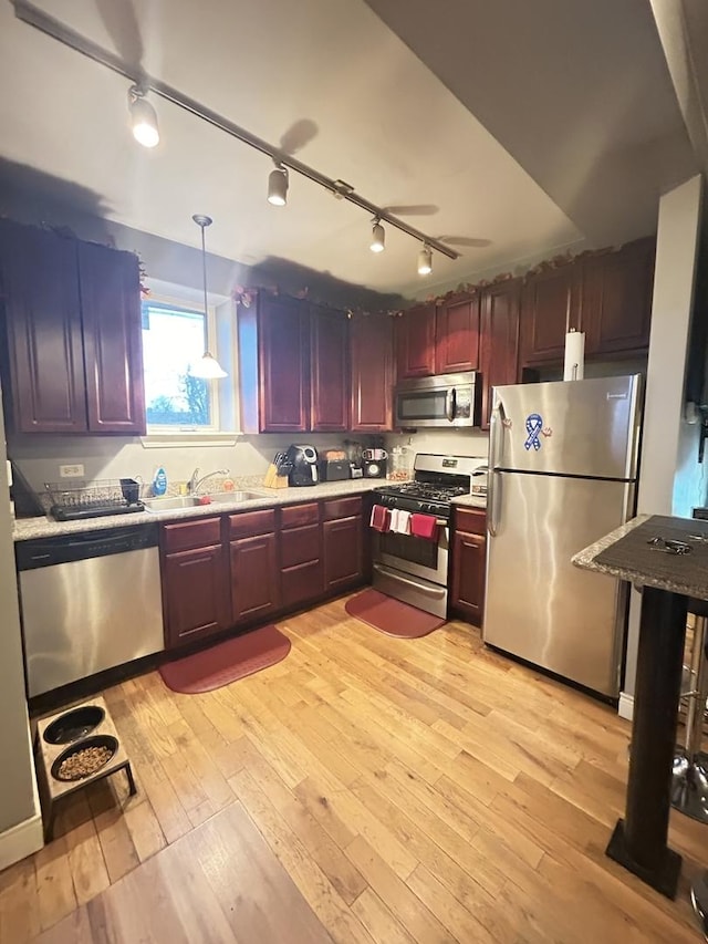 kitchen with pendant lighting, track lighting, sink, light hardwood / wood-style flooring, and stainless steel appliances