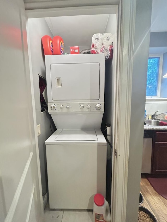 laundry area featuring sink, stacked washing maching and dryer, and light hardwood / wood-style floors