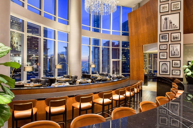 bar with hardwood / wood-style flooring, a towering ceiling, and a notable chandelier