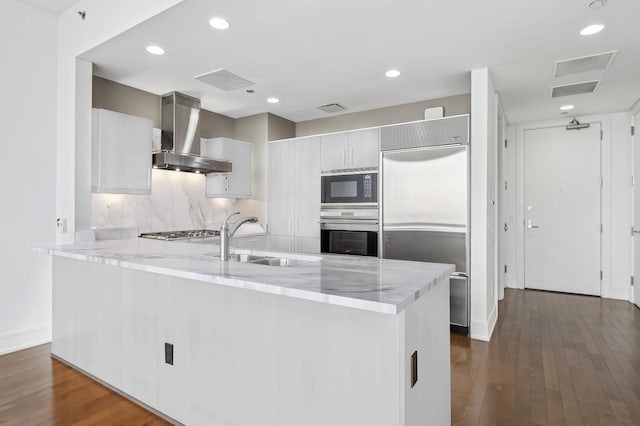 kitchen featuring sink, white cabinetry, built in appliances, dark hardwood / wood-style flooring, and exhaust hood