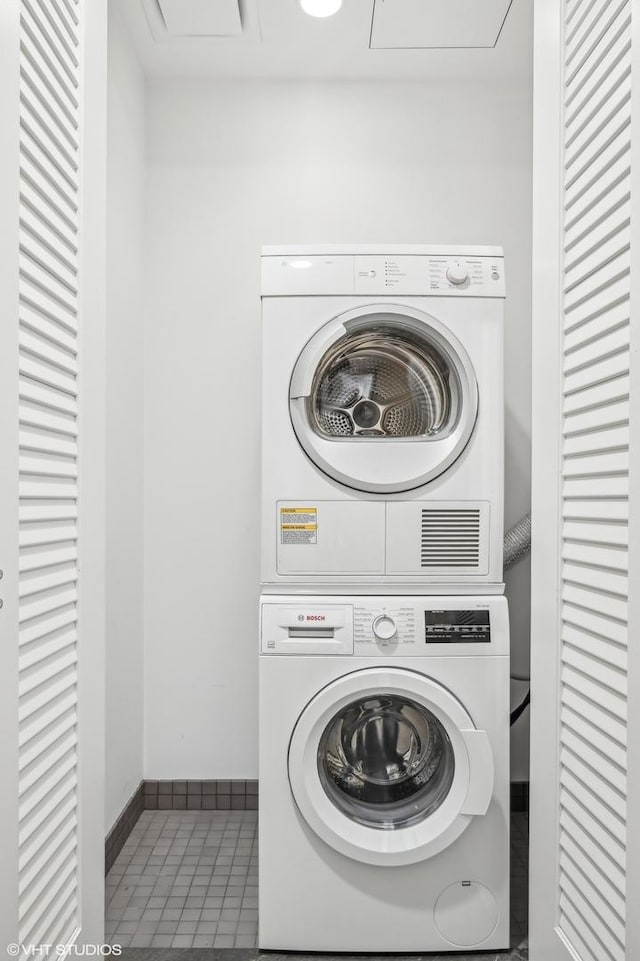 laundry area featuring tile patterned flooring and stacked washer and clothes dryer