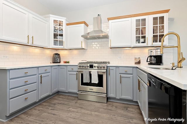 kitchen with wall chimney exhaust hood, sink, high end stainless steel range, white cabinets, and black dishwasher