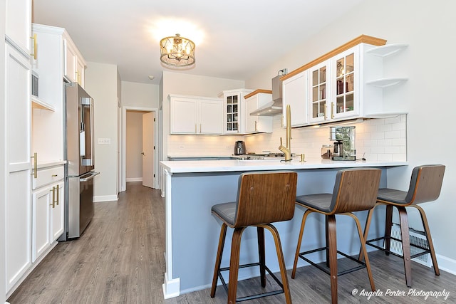 kitchen featuring kitchen peninsula, tasteful backsplash, white cabinetry, a breakfast bar area, and stainless steel appliances