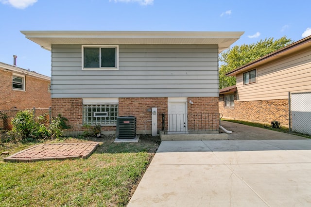 view of front of home with cooling unit and a front yard