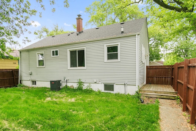 rear view of property featuring a deck, a yard, and central AC