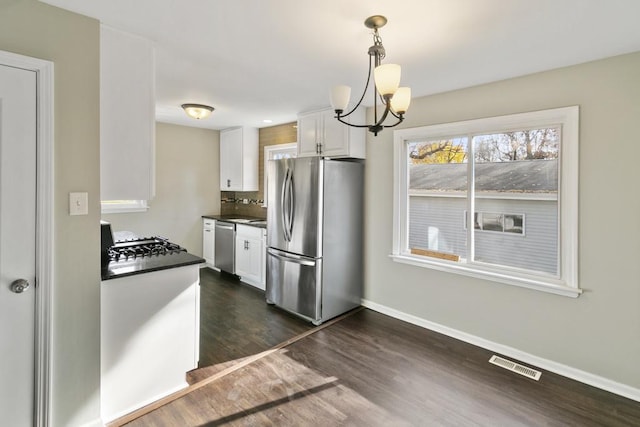 kitchen with white cabinetry, hanging light fixtures, stainless steel appliances, an inviting chandelier, and dark hardwood / wood-style floors