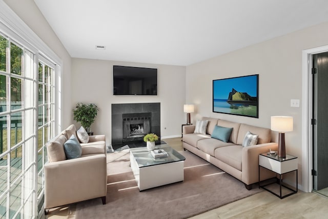 living room featuring a tile fireplace and wood-type flooring