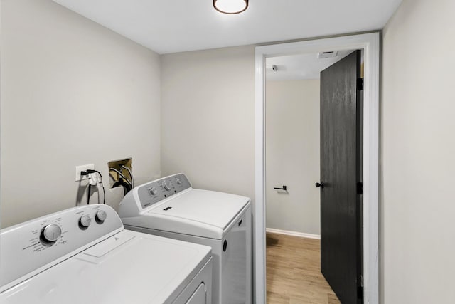 laundry area featuring washer and dryer and light hardwood / wood-style flooring