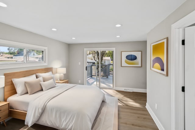 bedroom featuring access to exterior, multiple windows, and hardwood / wood-style flooring