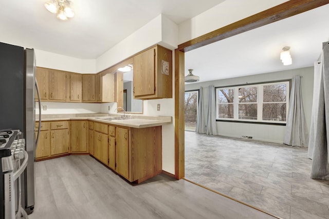 kitchen featuring stainless steel fridge, white gas stove, light hardwood / wood-style floors, and sink