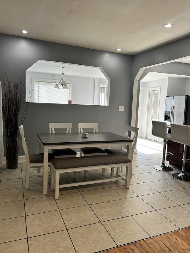 tiled dining space featuring plenty of natural light and an inviting chandelier