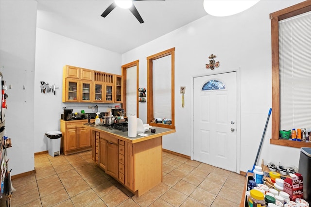 kitchen with light tile patterned floors, gas stovetop, a kitchen island, and ceiling fan