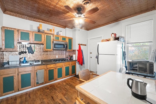 kitchen featuring appliances with stainless steel finishes, tasteful backsplash, ceiling fan, crown molding, and dark hardwood / wood-style floors