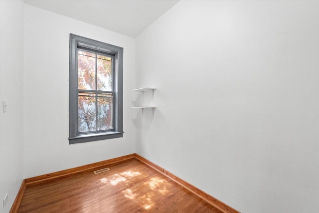 spare room with wood-type flooring and lofted ceiling