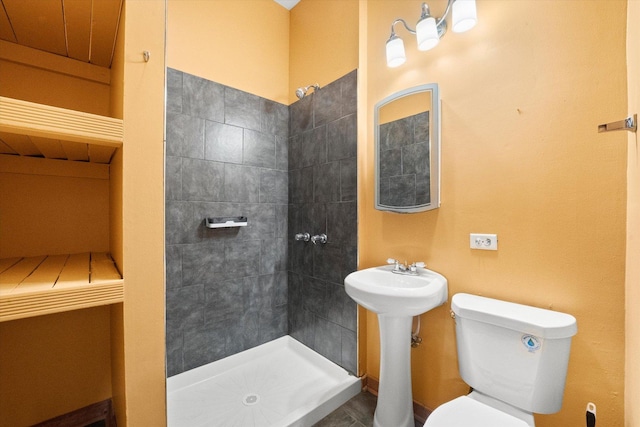 bathroom with a tile shower, tile patterned flooring, and toilet