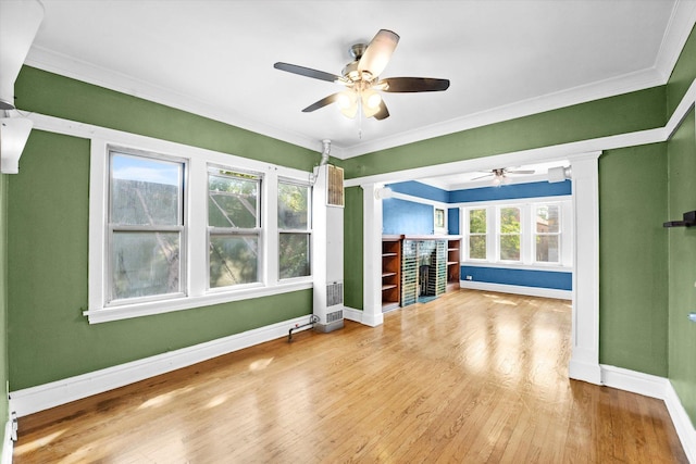 unfurnished living room with ceiling fan, ornamental molding, wood-type flooring, and a brick fireplace