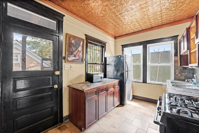 kitchen featuring stainless steel appliances, a wealth of natural light, crown molding, and sink