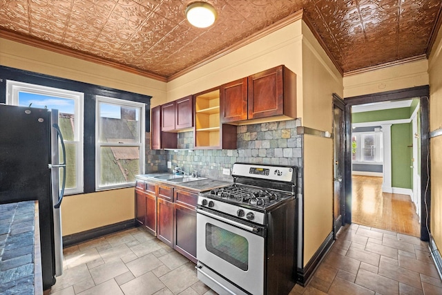 kitchen featuring sink, crown molding, fridge, decorative backsplash, and stainless steel range with gas stovetop