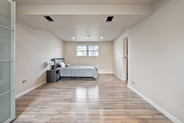 unfurnished bedroom with light hardwood / wood-style floors and wood walls