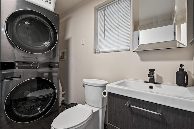 bathroom with vanity, stacked washer and clothes dryer, and toilet