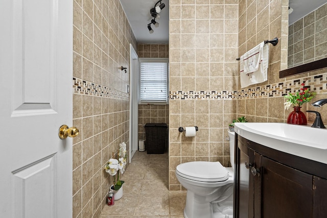 bathroom with tile patterned floors, vanity, toilet, and tile walls