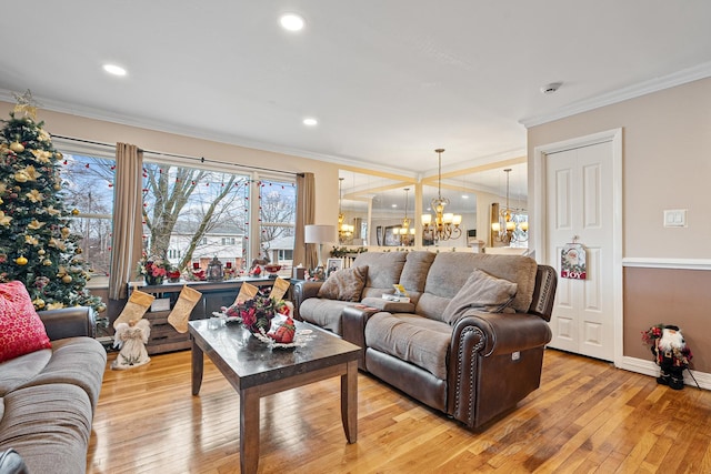 living room with light wood-type flooring, crown molding, and a notable chandelier