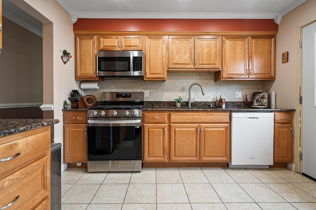 kitchen featuring backsplash, dark stone counters, sink, ornamental molding, and appliances with stainless steel finishes