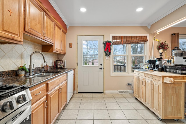 kitchen featuring dishwasher, crown molding, sink, stainless steel stove, and dark stone countertops